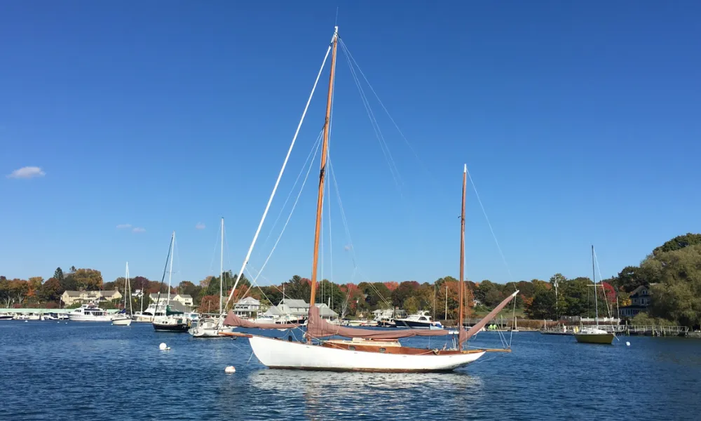 Sailboat on a mooring with fall trees in the background 